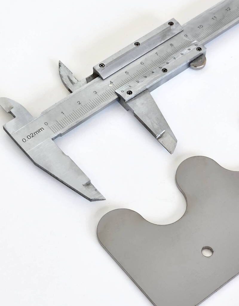 zdjęcie przedstawia miarkę, która mierzy odległość pomiędzy dwoma zaokrąglonymi wypustkami w elemencie.