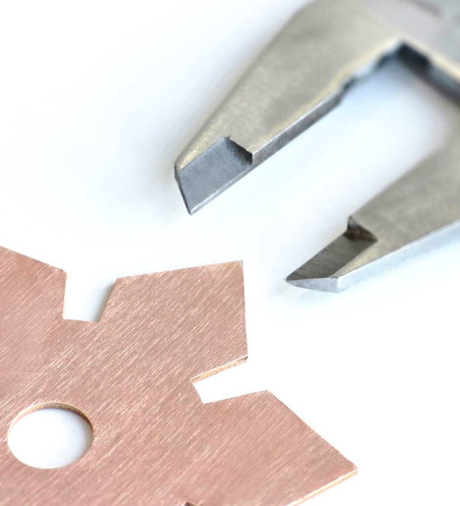 Zdjęcie przedstawia fragment kołą zębatego, ktry ma mierzone jedno ze swoich ramion za pomocą miarki.